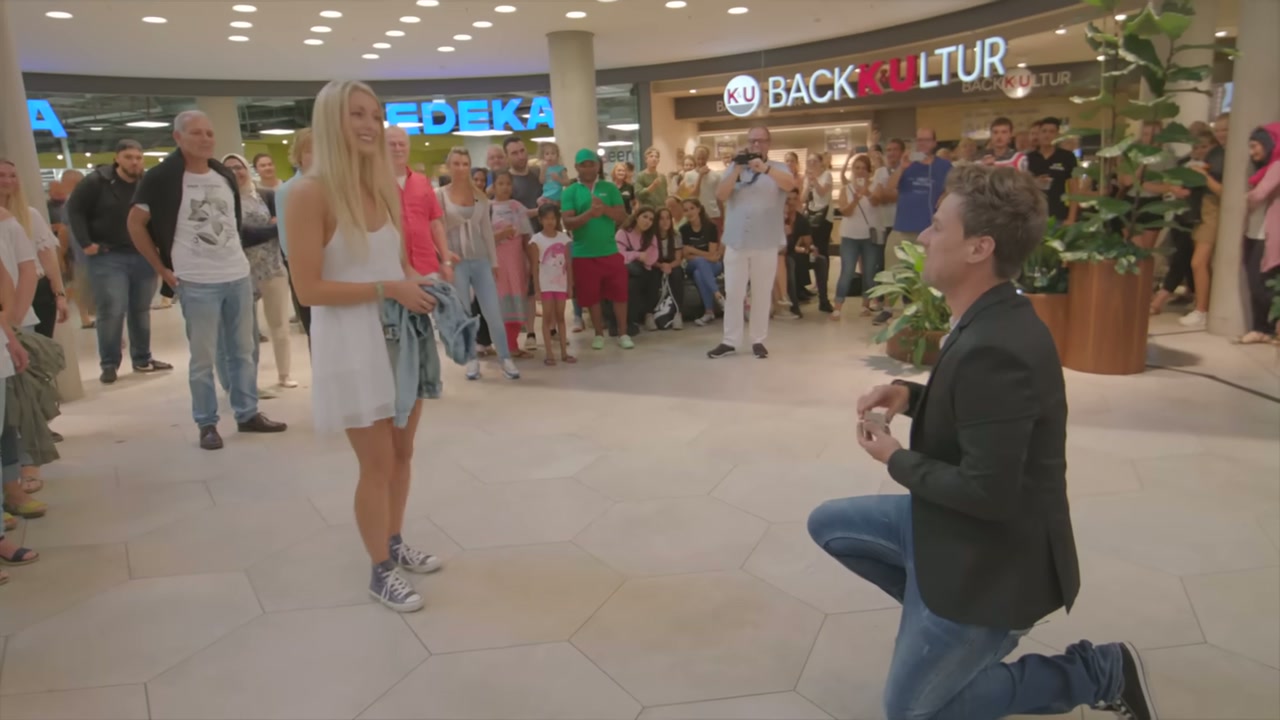 Robin Henderson kniet mit dem Ring vor Franziska, umringt von hunderten Menschen im Einkaufszentrum Gerber in Stuttgart